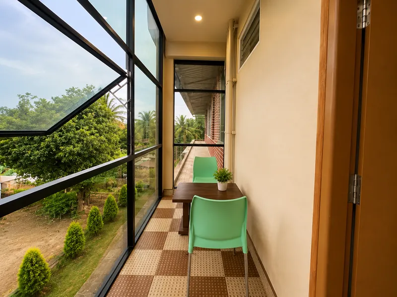 Glass-walled sit-out with a table and chairs looking into the trees